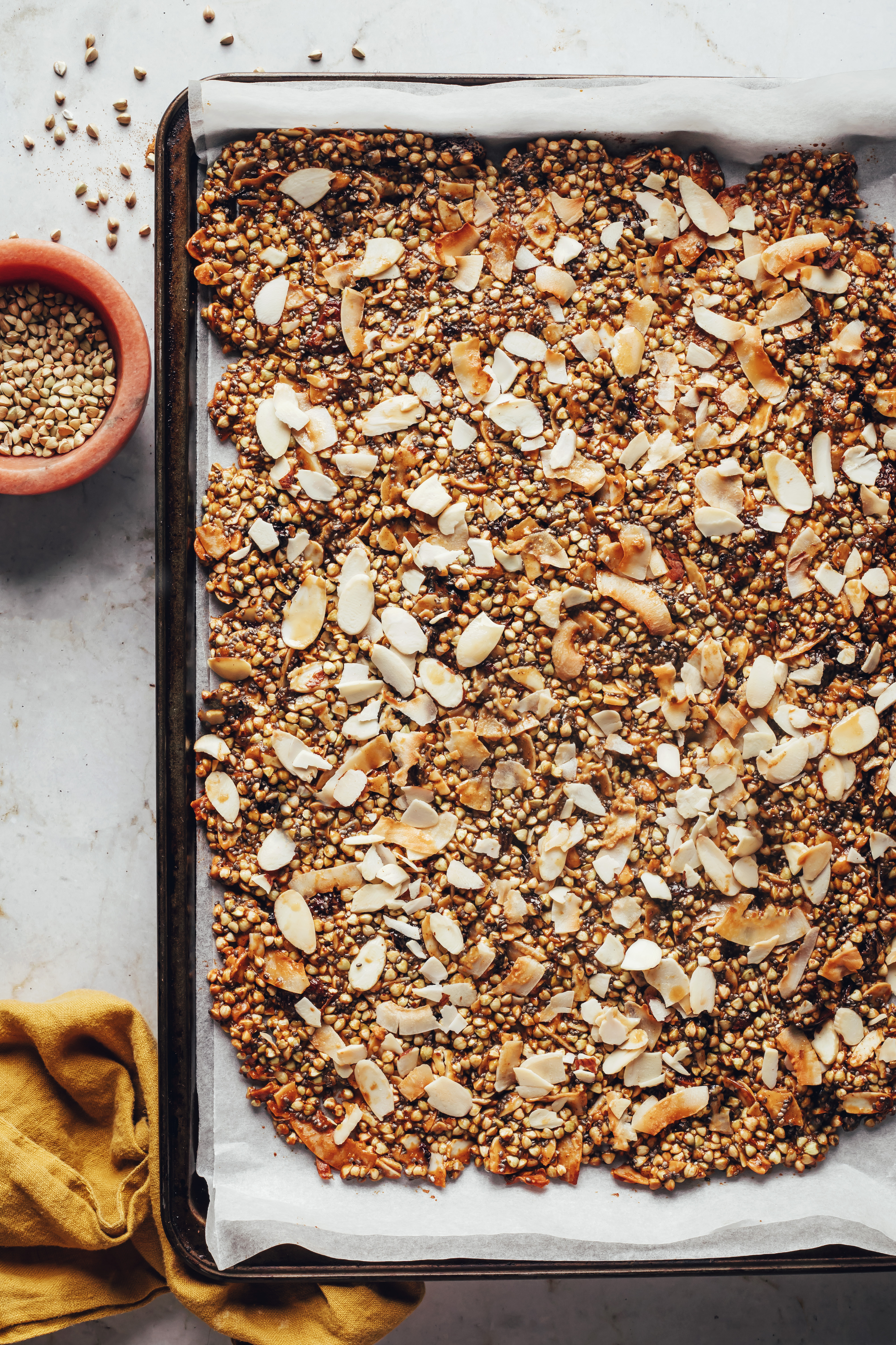 Granola spread on a baking sheet before baking