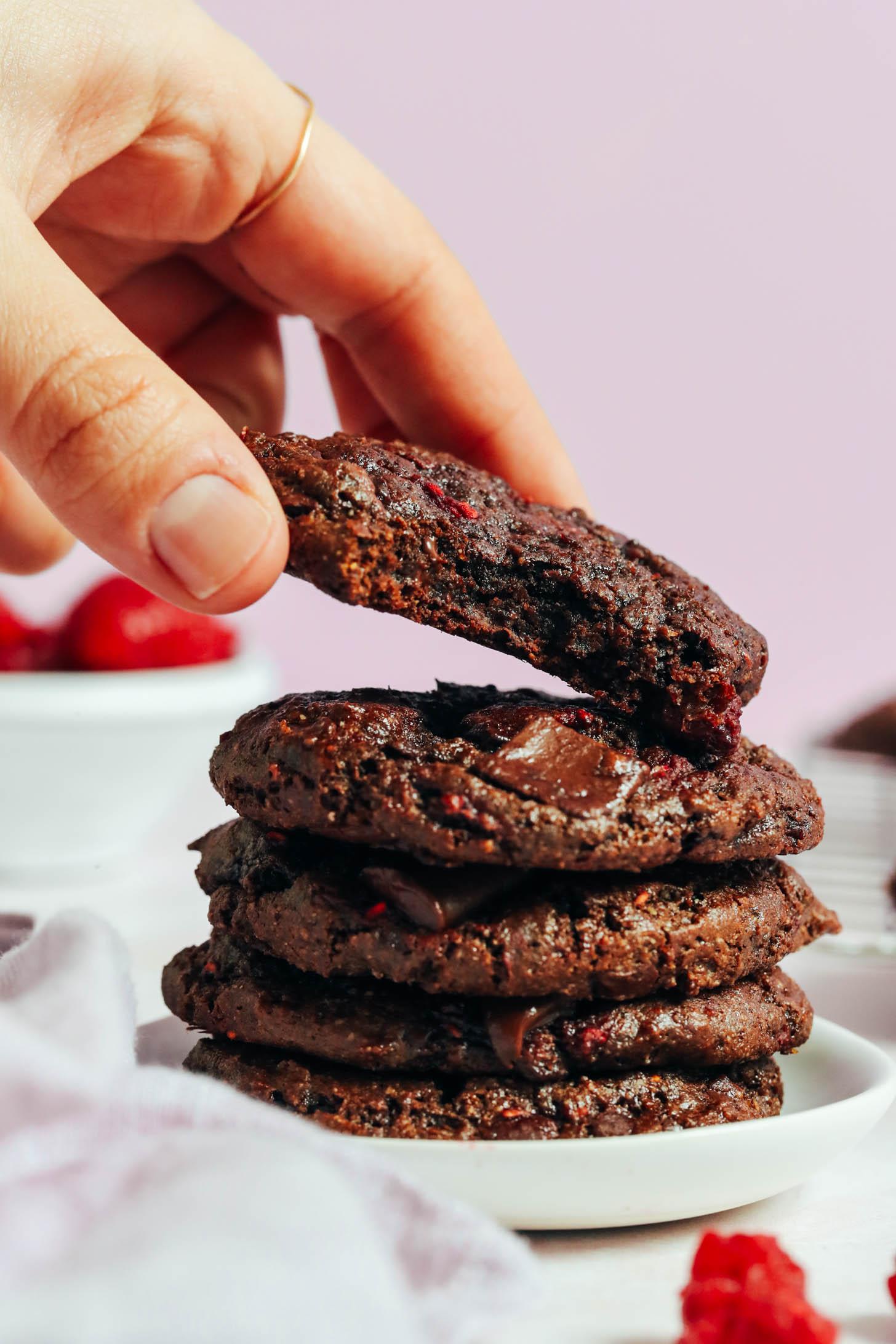 Placing a gluten-free chocolate cake mix cookie onto a stack of more cookies