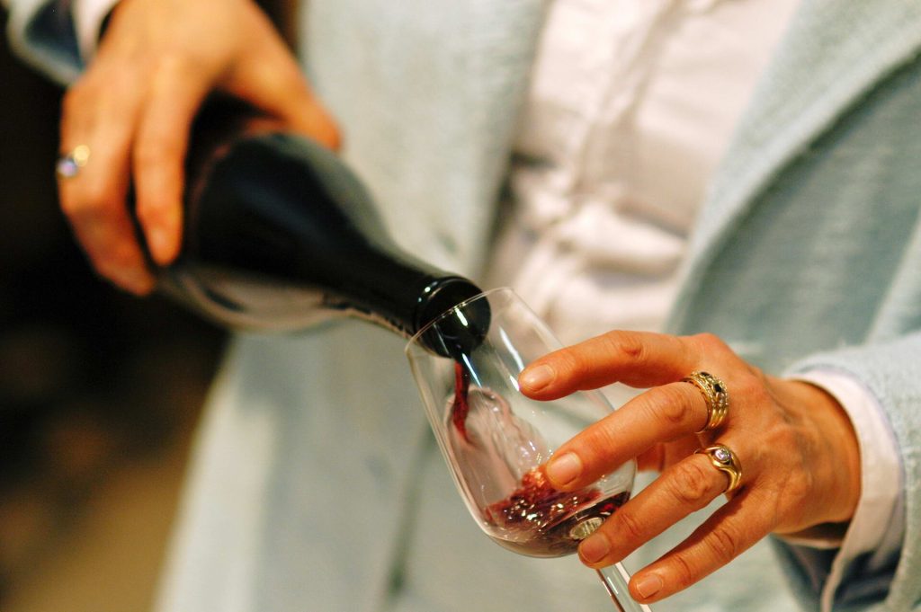 A glass of light, bright red wine on a wooden table