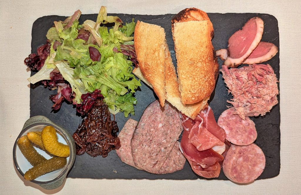 A charcuterie board with sliced sausage, pâté and bread