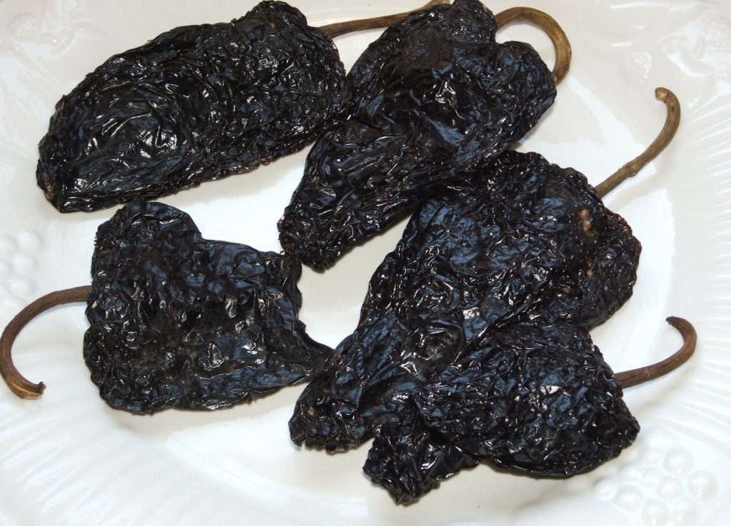 Dried ancho and guajillo chile peppers on a wooden board