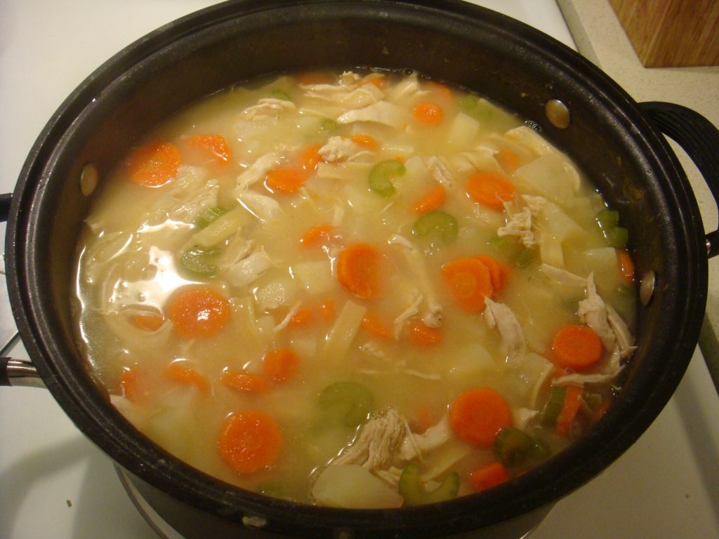 Chicken soup with carrots and celery simmering in a pot