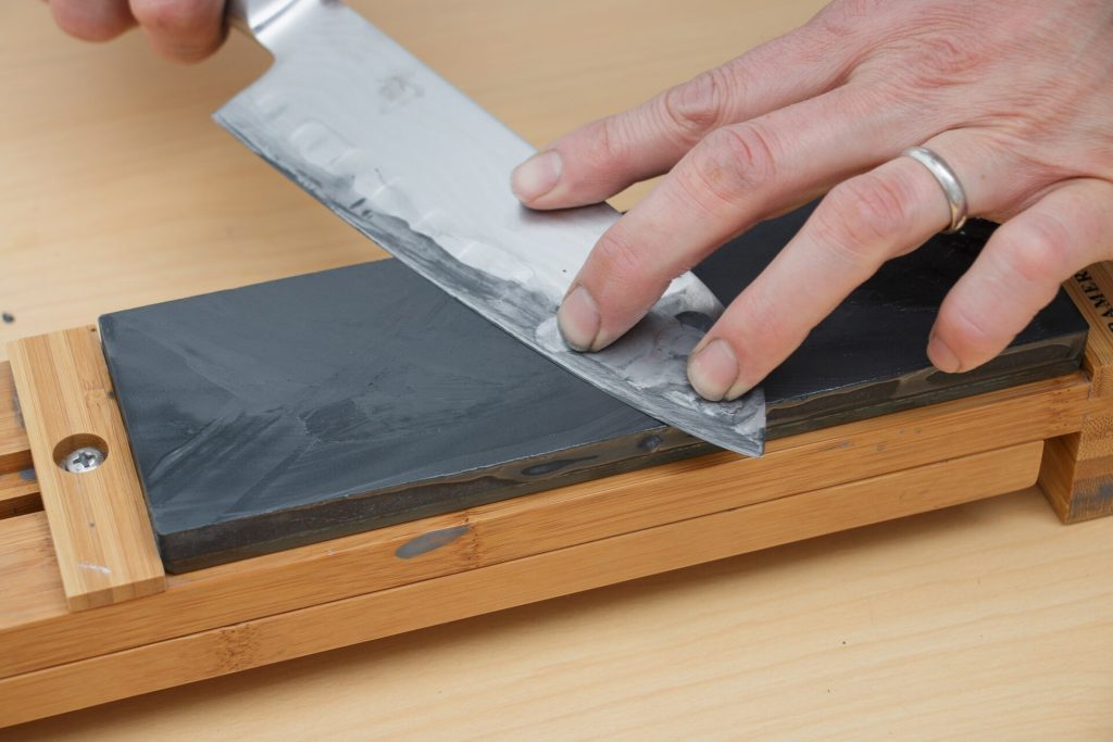A kitchen knife being sharpened on a whetstone