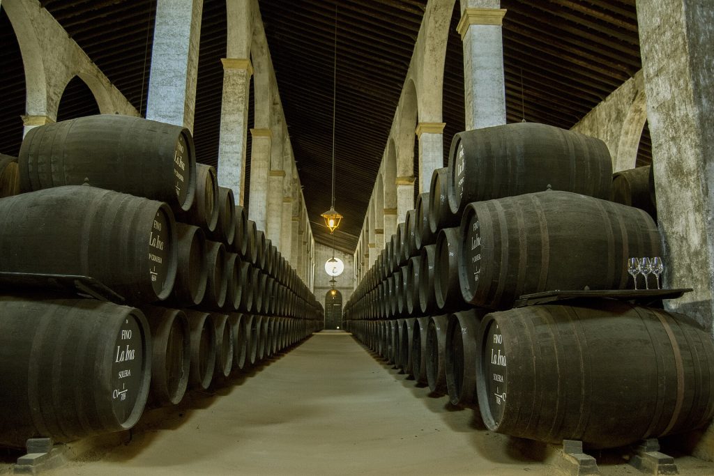 Rows of stacked oak sherry casks in a cellar